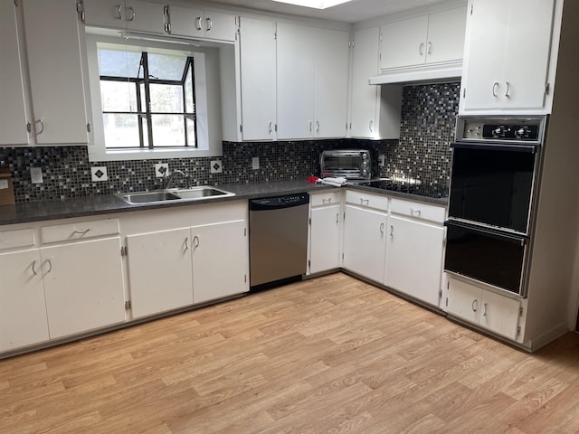 kitchen featuring dark countertops, decorative backsplash, light wood-style flooring, black appliances, and a sink