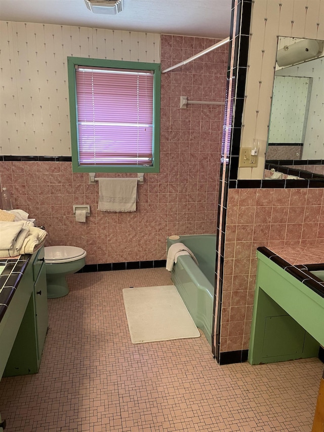 full bathroom featuring vanity, tile walls, toilet, and tub / shower combination