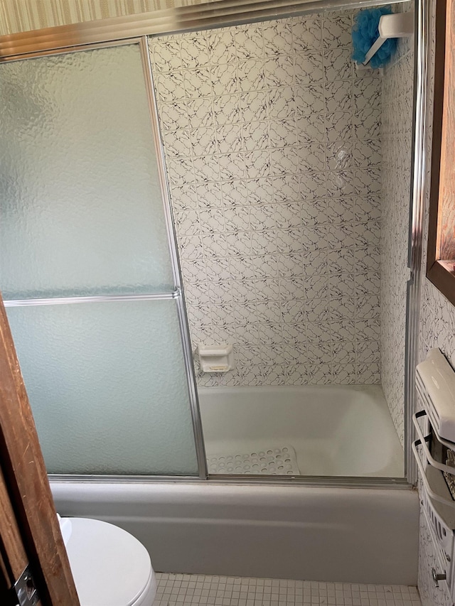 bathroom featuring tile patterned floors, toilet, and shower / bath combination with glass door