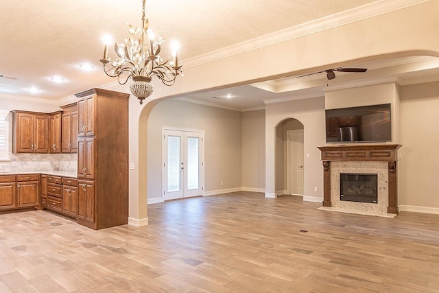 kitchen with french doors, ceiling fan with notable chandelier, crown molding, decorative backsplash, and a premium fireplace