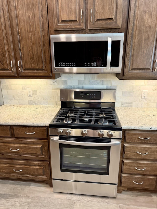 3865 E Pointe Dr, Beaumont, TX 77706 - kitchen with appliances with stainless steel finishes, dark brown cabinets, tasteful backsplash, and light stone countertops