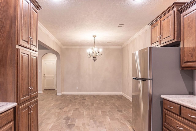 kitchen featuring light hardwood / wood-style floors, crown molding, stainless steel refrigerator, and a chandelier