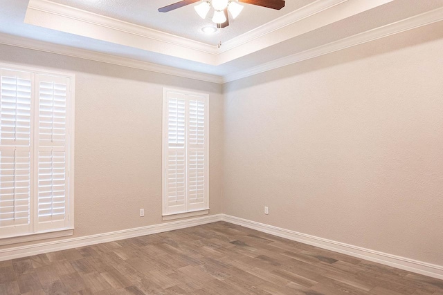 spare room with hardwood / wood-style flooring, ceiling fan, crown molding, and a tray ceiling