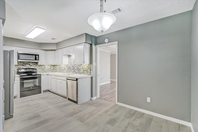 5960 Meadow Way, Beaumont, TX 77707 - kitchen with stainless steel appliances, light countertops, decorative backsplash, white cabinets, and light wood-style flooring