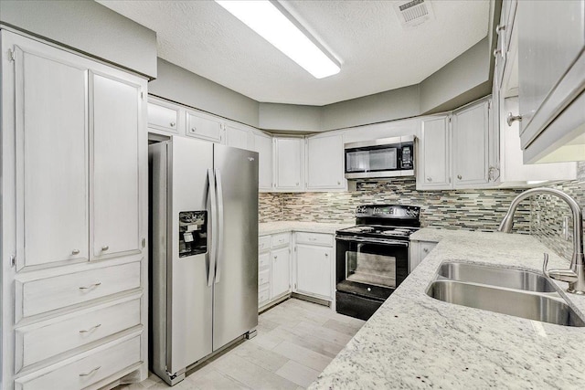 5960 Meadow Way, Beaumont, TX 77707 - kitchen with stainless steel appliances, a sink, decorative backsplash, white cabinets, and light stone counters