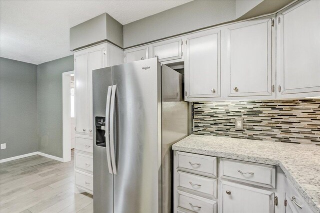 5960 Meadow Way, Beaumont, TX 77707 - kitchen with stainless steel fridge, light wood-style flooring, backsplash, baseboards, and white cabinets