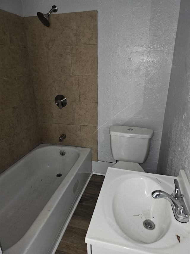 full bathroom featuring toilet, tiled shower / bath combo, wood-type flooring, and sink