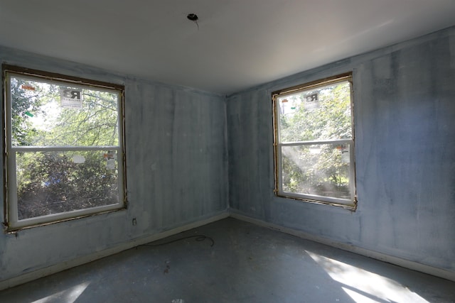 unfurnished room with concrete floors and a healthy amount of sunlight