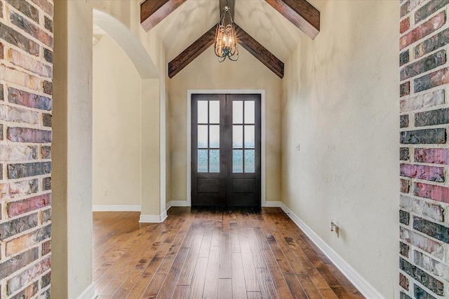 foyer featuring french doors, lofted ceiling with beams, and wood-type flooring