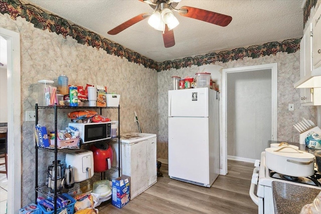 kitchen featuring white appliances, light wood-type flooring, a textured ceiling, white cabinetry, and extractor fan