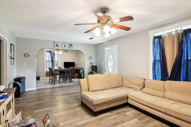 living room featuring a textured ceiling, light hardwood / wood-style flooring, and ceiling fan