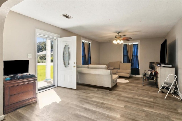 living room featuring ceiling fan, a textured ceiling, and light hardwood / wood-style flooring