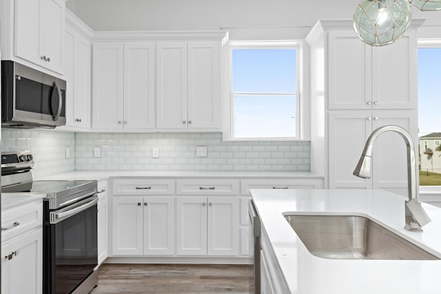 kitchen with decorative backsplash, appliances with stainless steel finishes, sink, hardwood / wood-style flooring, and white cabinets