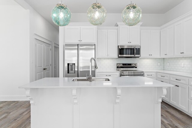 kitchen with decorative light fixtures, an island with sink, white cabinets, and appliances with stainless steel finishes