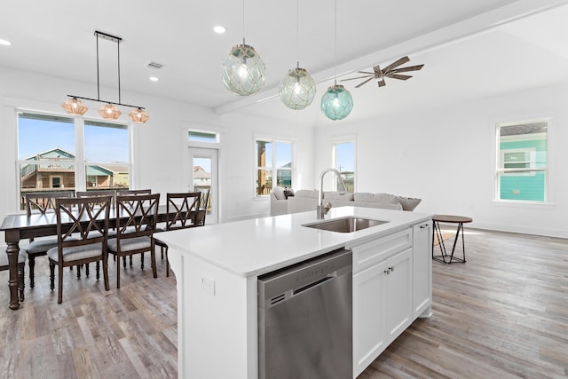 kitchen with stainless steel dishwasher, a kitchen island with sink, sink, pendant lighting, and white cabinets