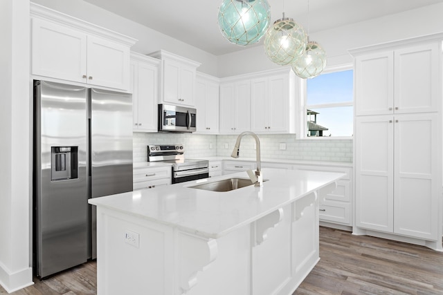 kitchen with pendant lighting, sink, stainless steel appliances, and a kitchen island with sink