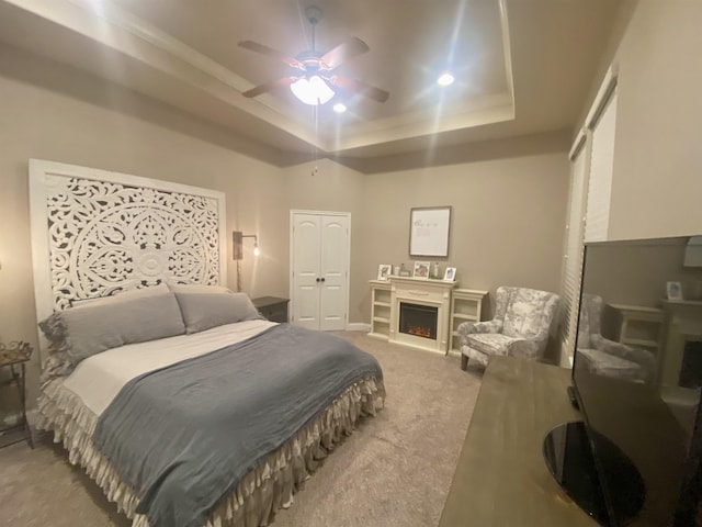 carpeted bedroom featuring ceiling fan and a raised ceiling