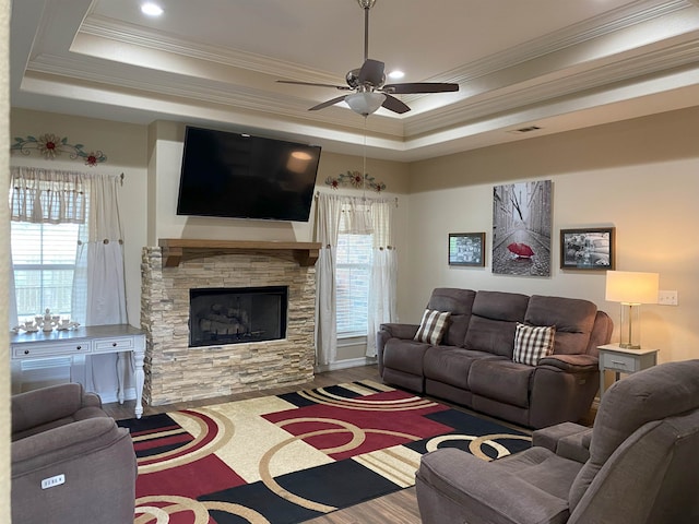 living area featuring a wealth of natural light, visible vents, a raised ceiling, and ceiling fan