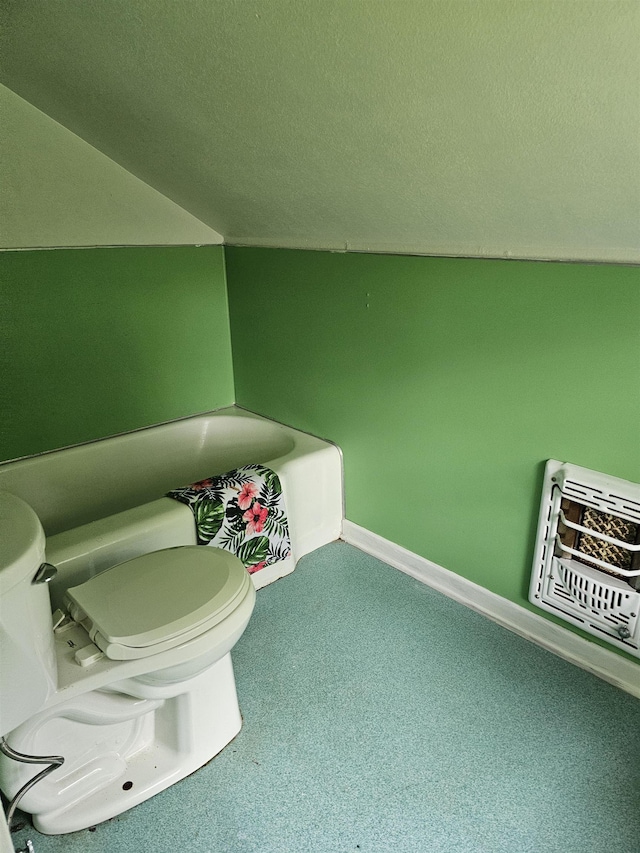 bathroom with vaulted ceiling, a washtub, toilet, a textured ceiling, and heating unit