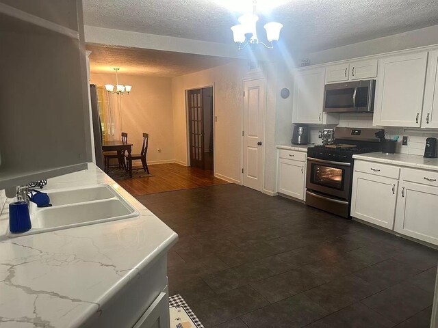 kitchen featuring white cabinets, stainless steel appliances, hanging light fixtures, and an inviting chandelier