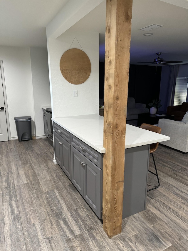 kitchen with dark hardwood / wood-style flooring, gray cabinets, a kitchen breakfast bar, and ceiling fan