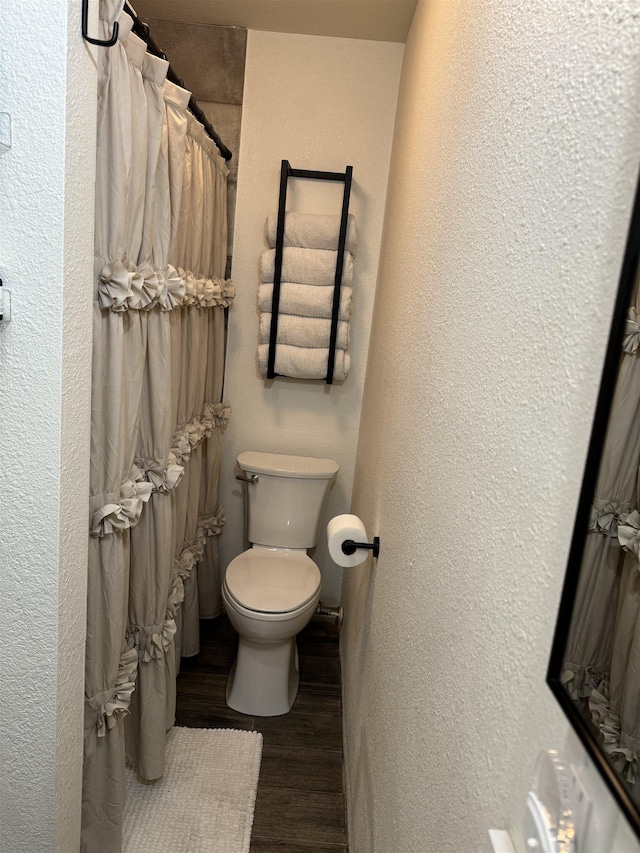 bathroom with hardwood / wood-style flooring, toilet, and a shower with shower curtain