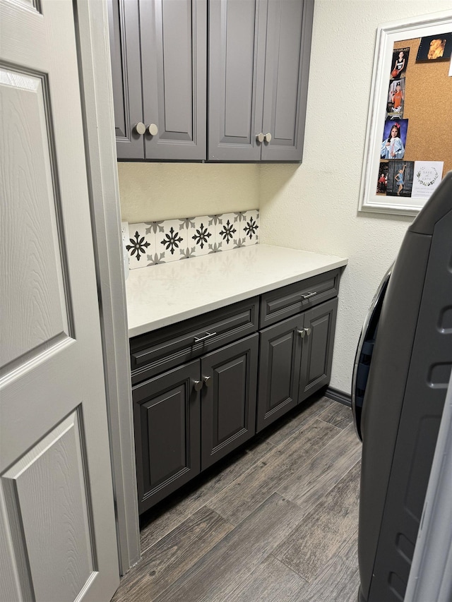 laundry area with dark hardwood / wood-style flooring and cabinets