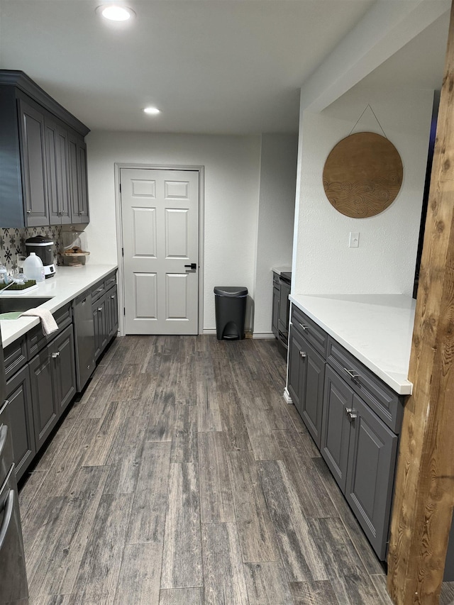 kitchen with dark hardwood / wood-style flooring, backsplash, gray cabinets, and stainless steel dishwasher