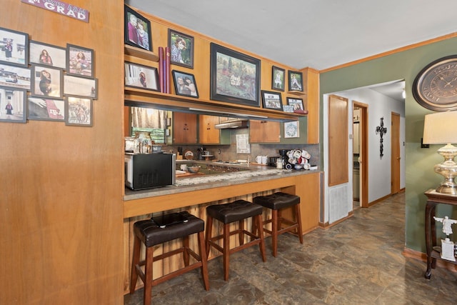 2836 Old Spurger Rd, Silsbee, TX 77656 - kitchen with stone finish flooring, black microwave, brown cabinets, decorative backsplash, and a breakfast bar