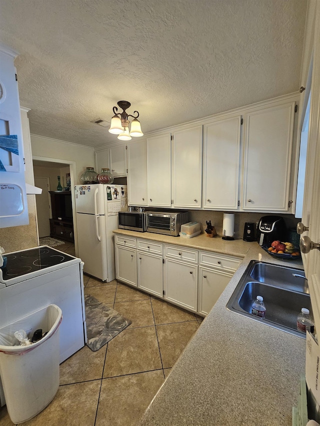 kitchen featuring sink, light tile patterned floors, a textured ceiling, white appliances, and white cabinets