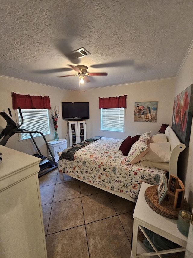 tiled bedroom featuring ceiling fan, a textured ceiling, and ornamental molding