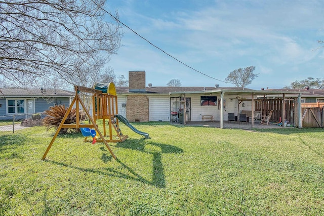 rear view of house featuring fence, a yard, a chimney, a playground, and a patio area