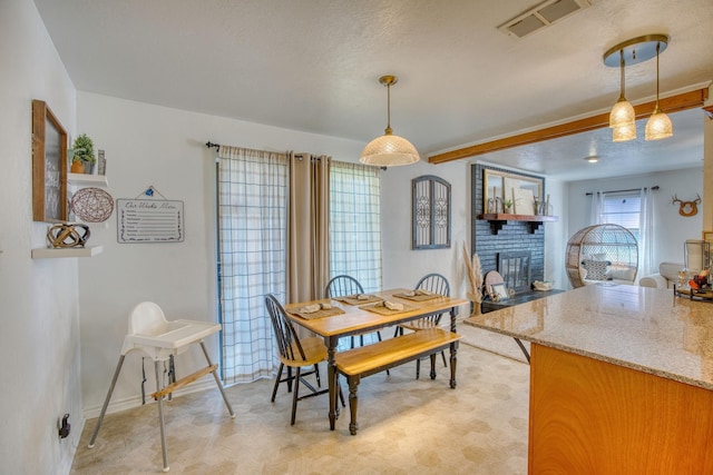 dining space featuring visible vents, baseboards, a textured ceiling, and a brick fireplace