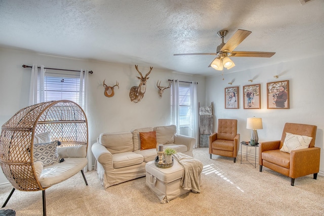 living area featuring light colored carpet, a ceiling fan, and a textured ceiling