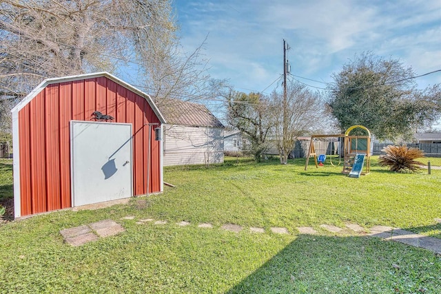 view of yard with a storage shed, an outdoor structure, a playground, and fence