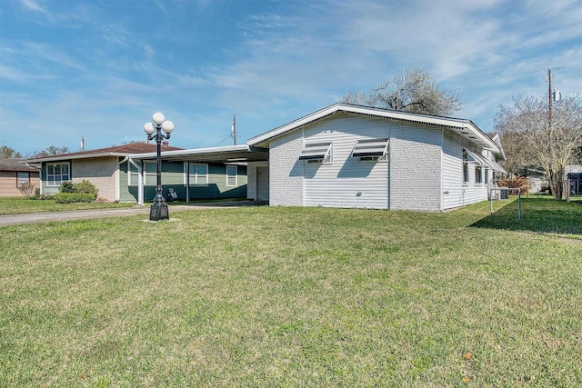 exterior space featuring an attached carport, a front lawn, brick siding, and driveway