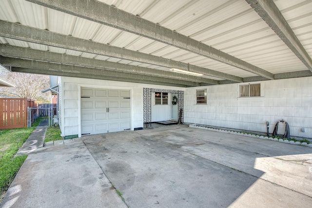 garage featuring an attached carport and fence