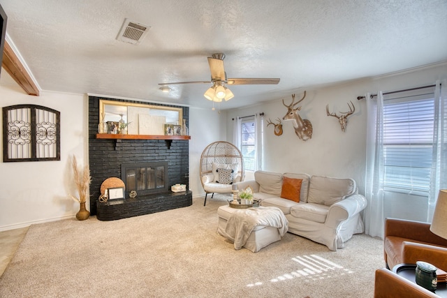 carpeted living room with visible vents, a textured ceiling, baseboards, a brick fireplace, and ceiling fan