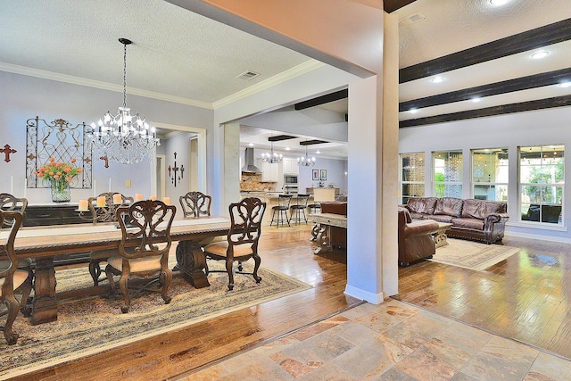 dining space with visible vents, light wood-style flooring, ornamental molding, a textured ceiling, and a notable chandelier