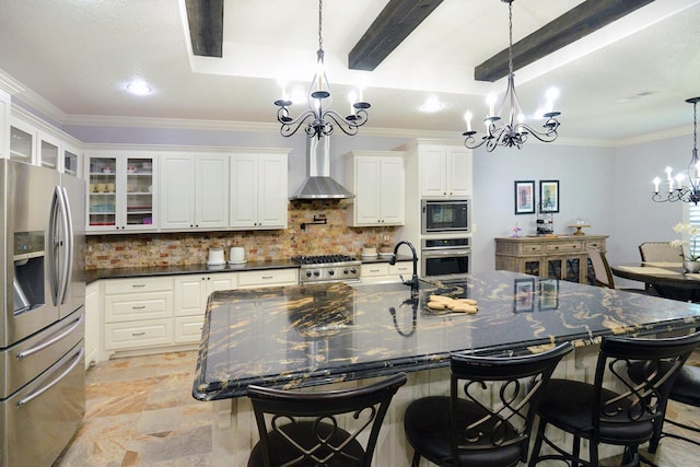 kitchen with a sink, decorative backsplash, stainless steel appliances, wall chimney range hood, and a chandelier