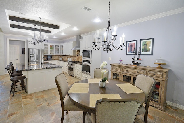 dining room with a raised ceiling, visible vents, stone tile flooring, and a chandelier