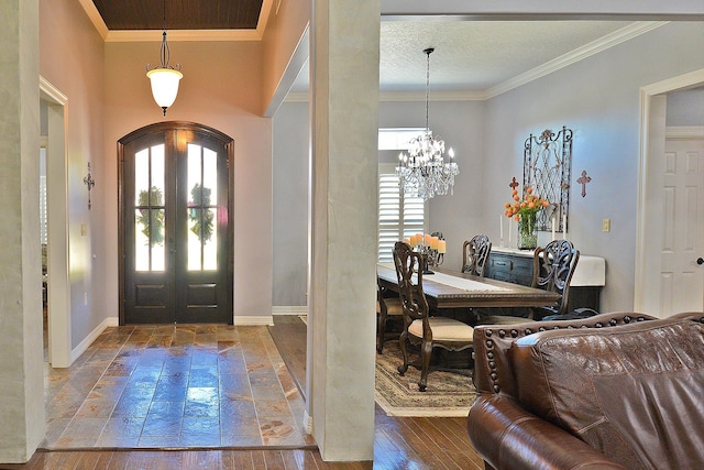 entrance foyer featuring ornamental molding, hardwood / wood-style flooring, french doors, arched walkways, and a chandelier