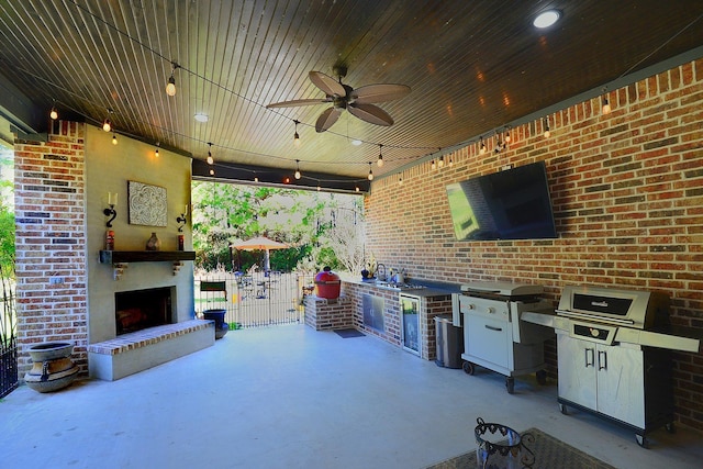 view of patio with grilling area, ceiling fan, fence, an outdoor fireplace, and an outdoor kitchen