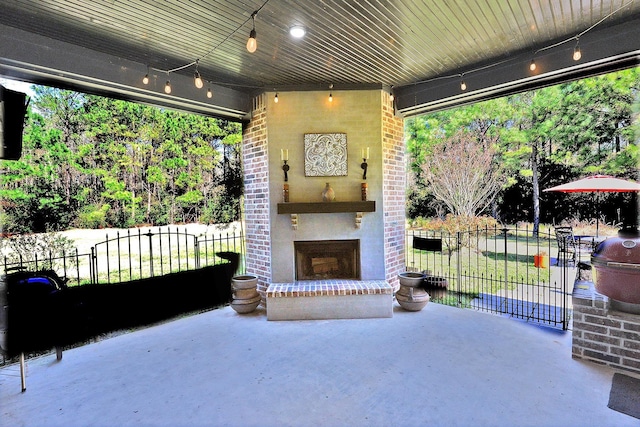 view of patio featuring an outdoor brick fireplace and fence