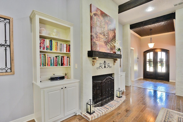 entryway with visible vents, beam ceiling, french doors, arched walkways, and light wood finished floors