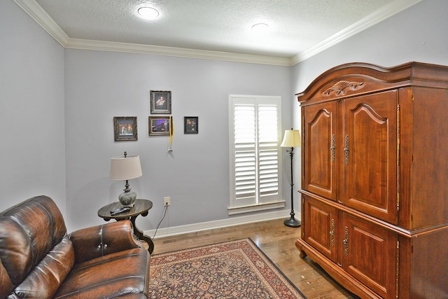 sitting room with a textured ceiling, wood finished floors, baseboards, and ornamental molding