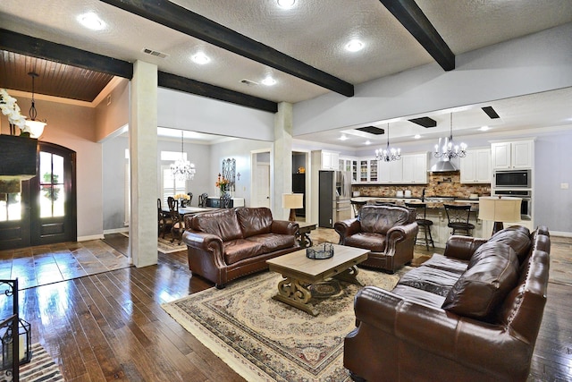 living area featuring visible vents, a chandelier, beam ceiling, dark wood-style floors, and a textured ceiling