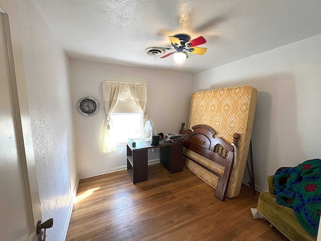 bedroom featuring a textured ceiling, visible vents, hardwood / wood-style flooring, and baseboards