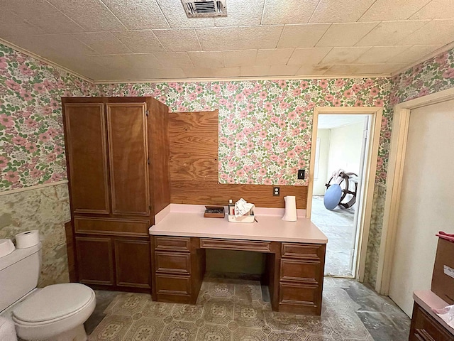 bathroom with a wainscoted wall, visible vents, toilet, and wallpapered walls