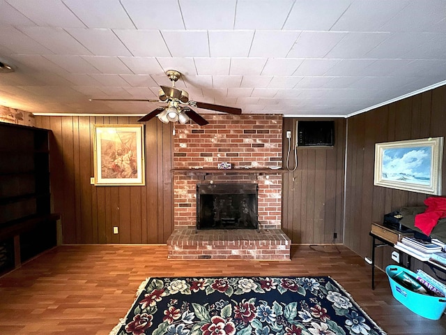 living room with a wall unit AC, a fireplace, wooden walls, and wood finished floors